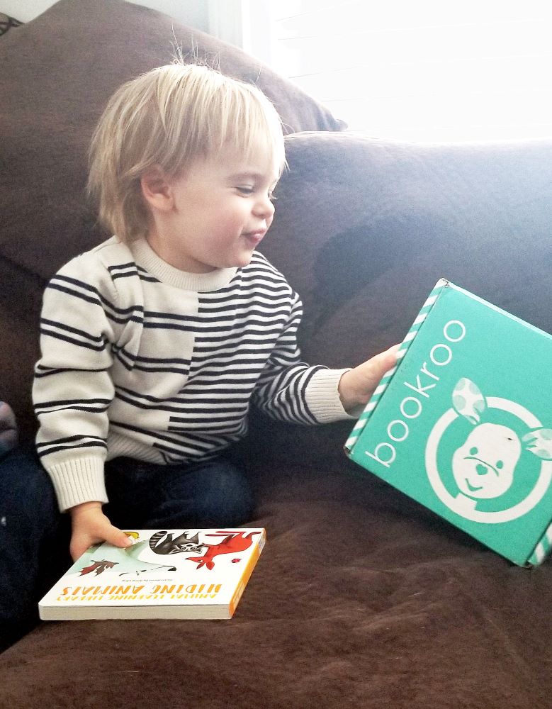 toddler grinning at bookroo box of books