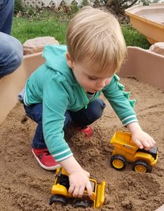 toddler playing in sandbox