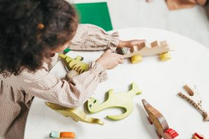 Canva - Overhead Photo of Young Girl Playing with Wooden Toys on White Table