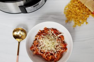 chicken marinara in bowl with slow cooker and egg noodles
