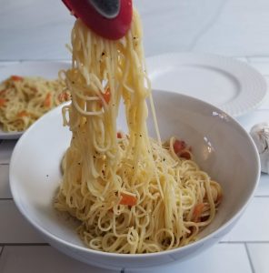 tongs pulling spaghetti with garlic olive oil