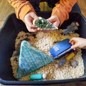 hands playing with forest camping sensory bin